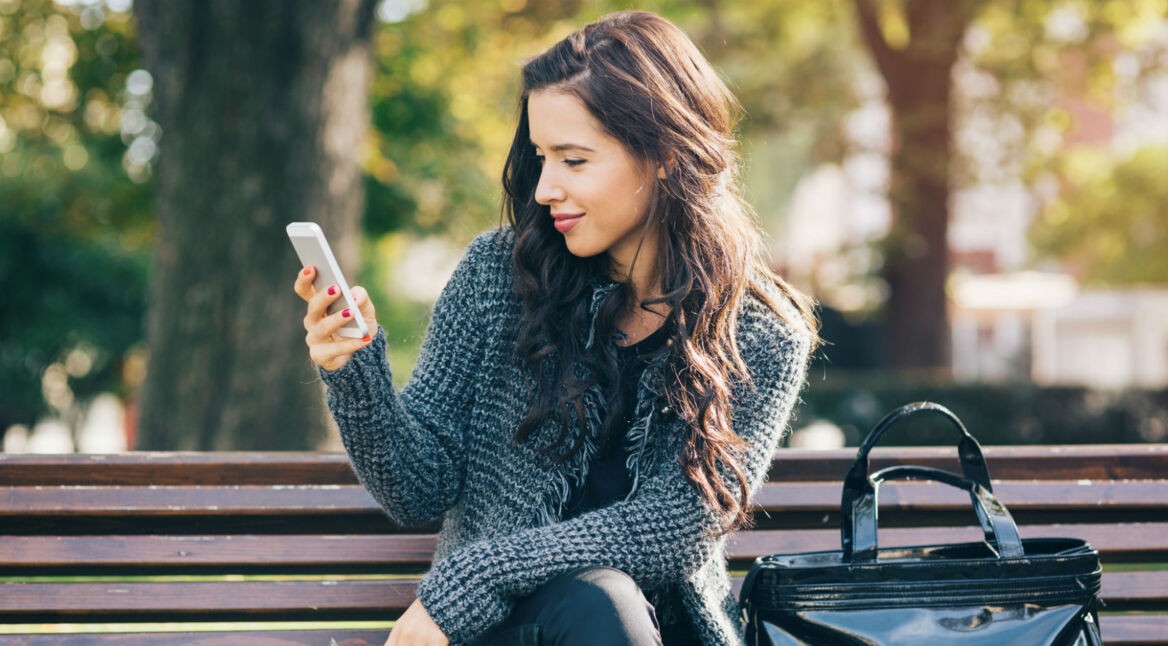 Junge Frau öffnet die Alexa-App auf ihrem Smartphone.