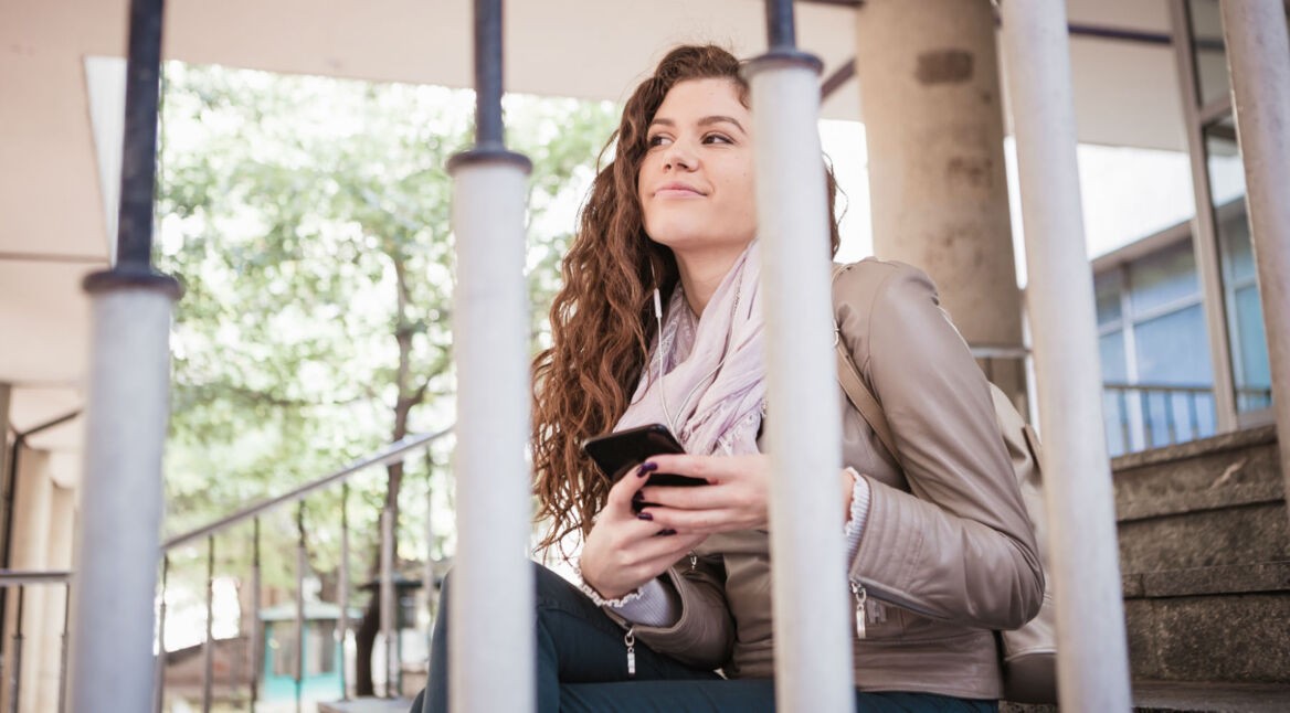 Junge Frau meldet sich am Smartphone von Facebook ab.