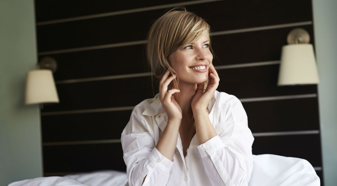 Junge Frau wacht morgens in ihrem Bett auf.