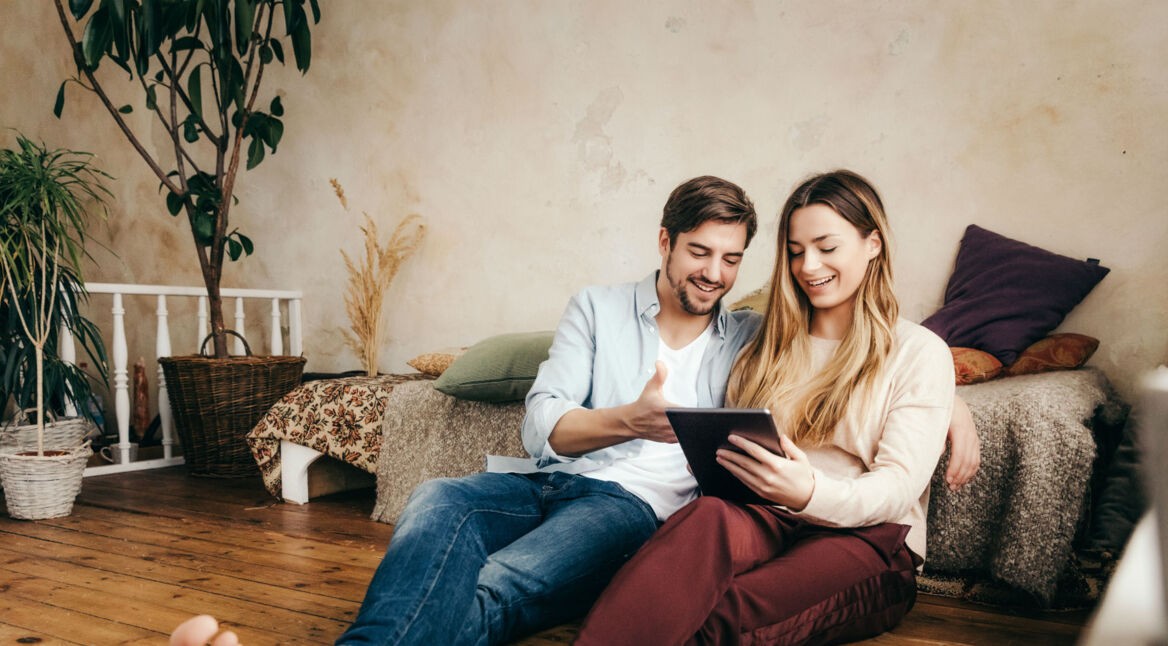 Junges Paar spielt mit dem Tablet im Wohnzimmer.