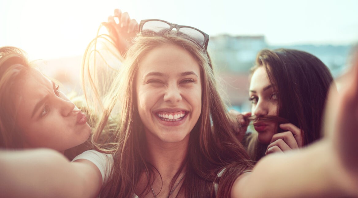 Group of Smiling Girls Taking Funny Selfie Outdoors at Sunset