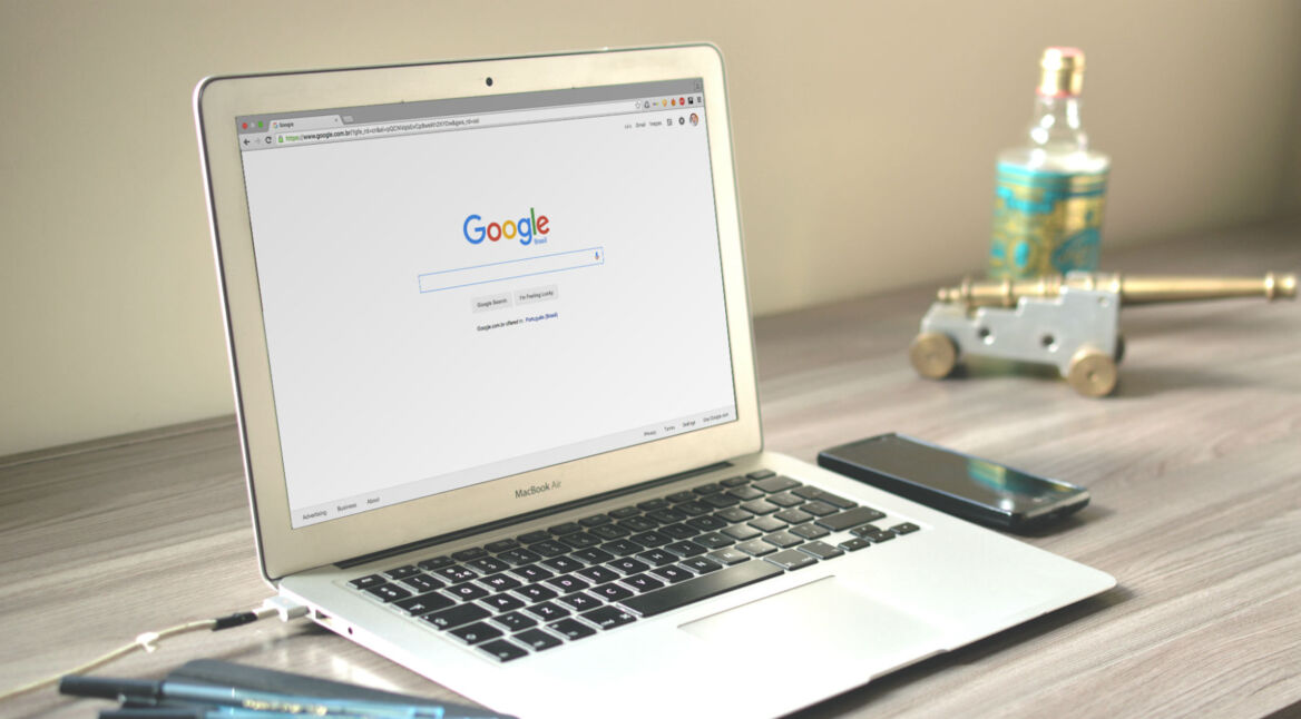 Weißes Macbook Air liegt auf einem Schreibtisch.