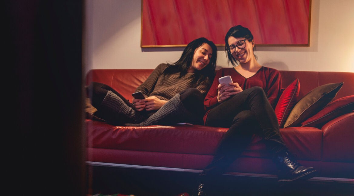 Zwei Frauen suchen das Fernsehprogramm via Smartphone aus