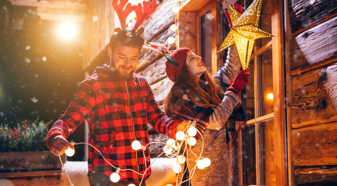 Junges Paar hängt leuchtende Weihnachtsdekoration auf