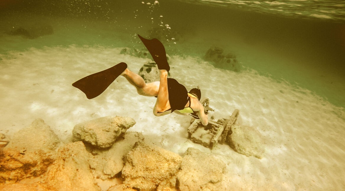 Junger Taucher taucht und nimmt ein Foto mit seiner Kamera auf.