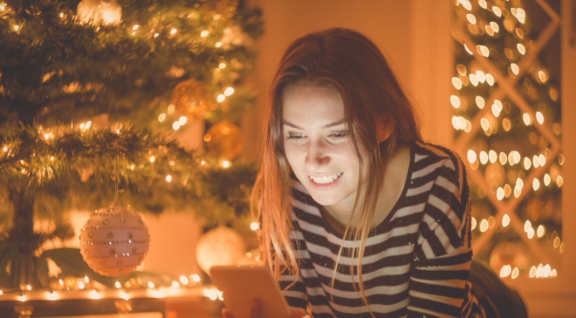 Eine Frau verschickt Weihnachtsgrüße via Smartphone