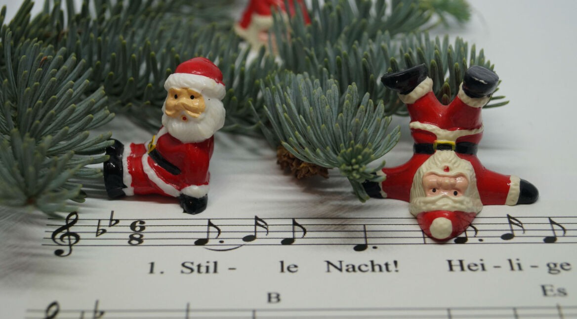 Weihnachtsmänner-Figuren liegen neben Liedtext von "Stille Nacht, Heilige Nacht".