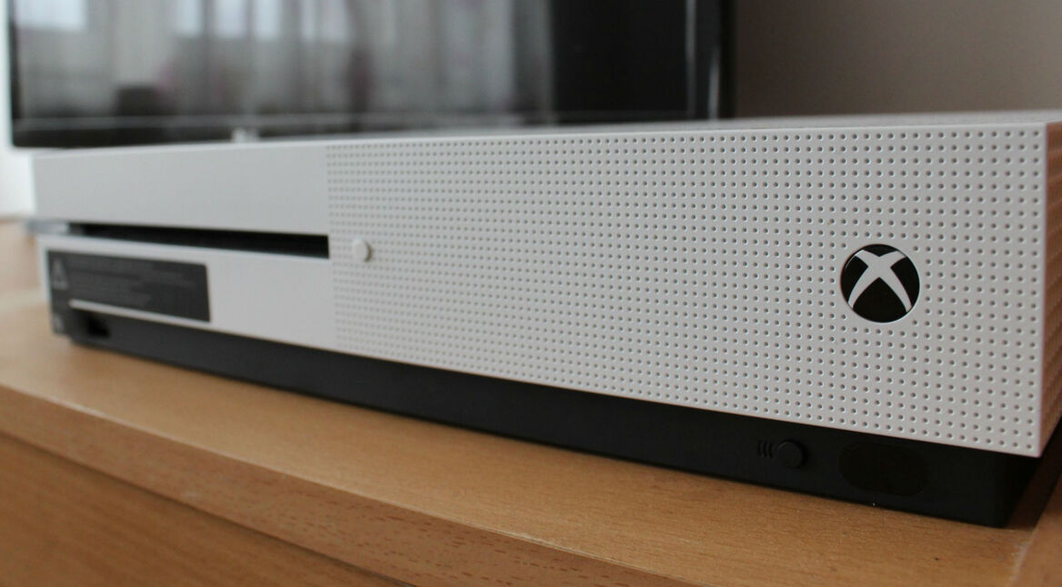 Weiße Xbox One S-Konsole liegt auf einem Holztisch.