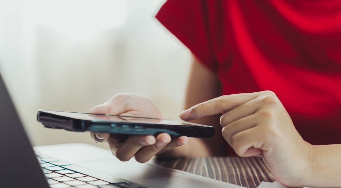 Frau tippt mit ihrem Finger auf ein Smartphone.