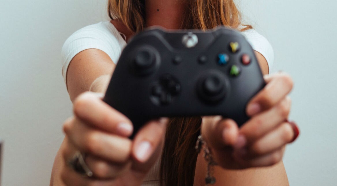 Junge Frau zockt mit dem Xbox One-Controller.