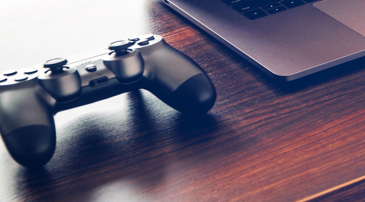 Ein PlayStation 4-Controller neben einem Laptop