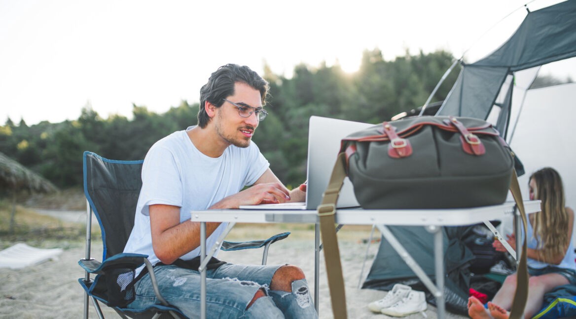 Mann beim Camping hilft einem Freund mit iPhone