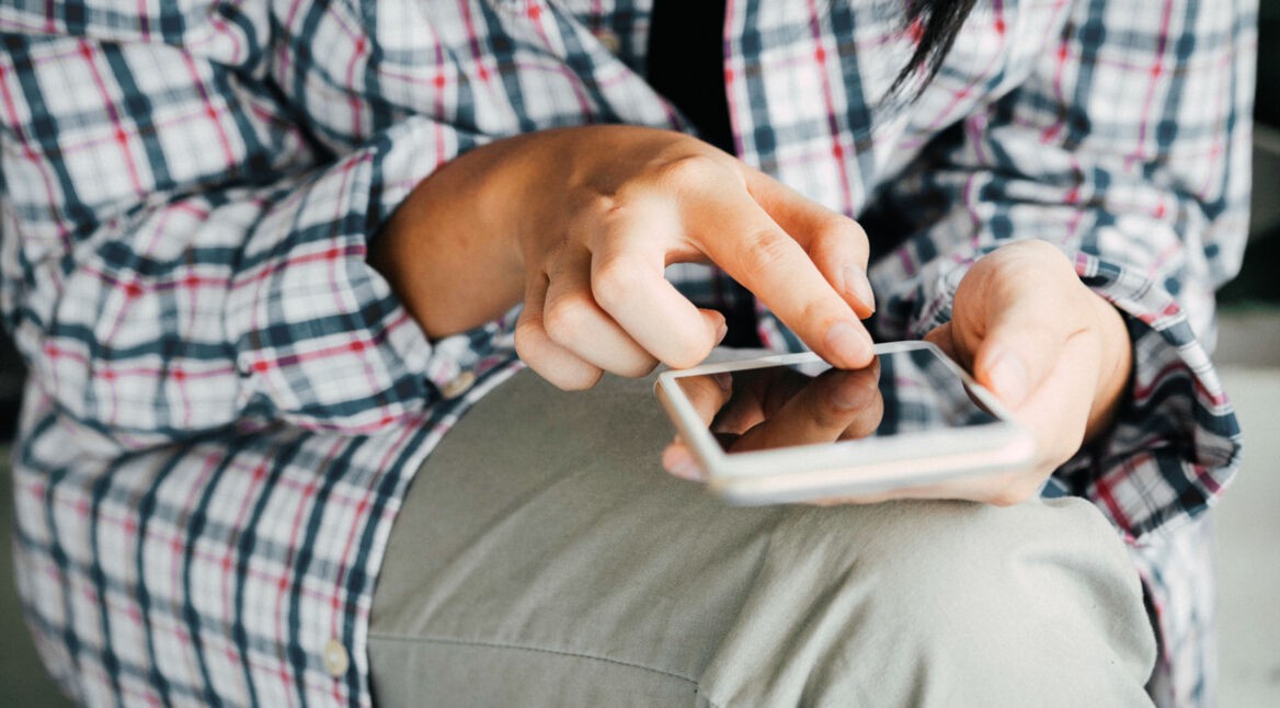 Junge Frau probiert den Dark Mode auf ihrem iPhone aus.
