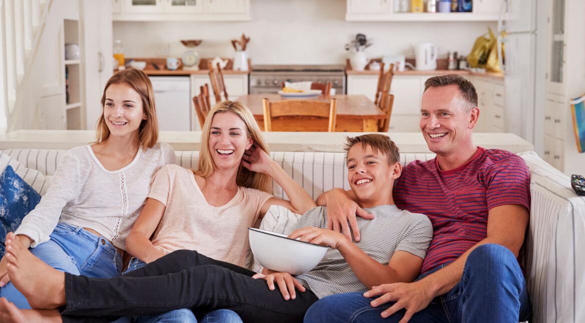 Family With Teenage Children Sitting On Sofa Watching TV Together