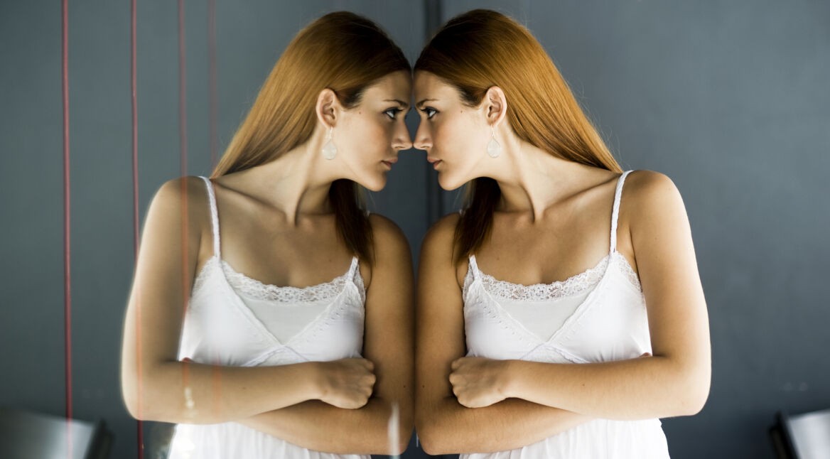 Woman in a white dress staring at her own reflection