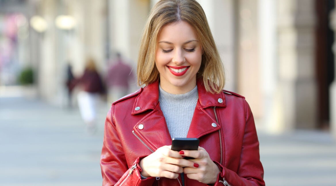 Junge Frau schreibt eine WhatsApp-Nachricht an ihrem Smartphone.