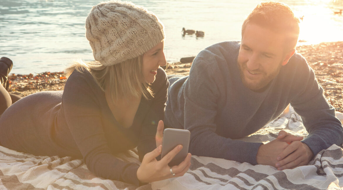Junges Paar nutzt Smartphone am Strand