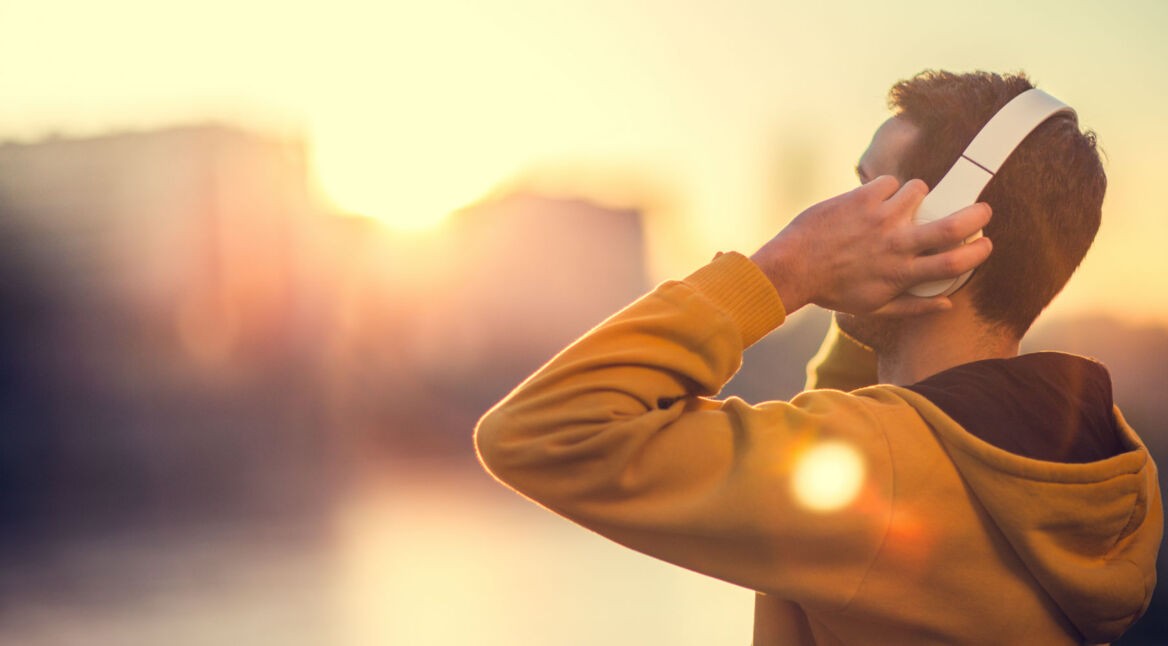 Junger Mann hört Musik über seine drahtlosen Kopfhörer.