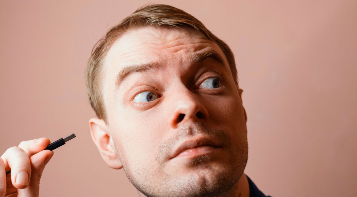 Ein Mann horcht an einem USB-Stecker