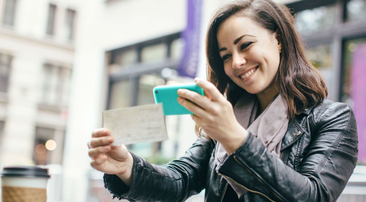 Junge Frau fotografiert ein Dokument mit dem Smartphone ab.