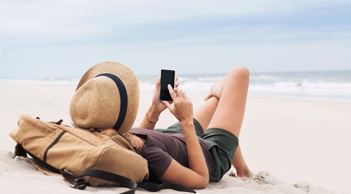 Frau mit Smartphone am Strand