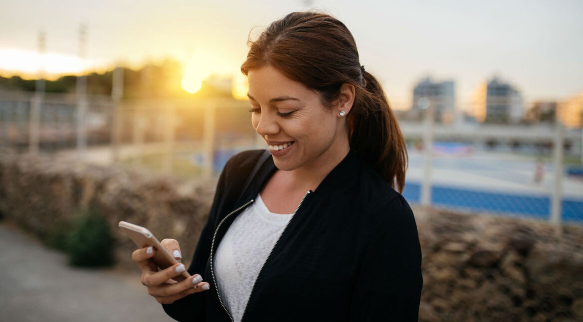Junge Frau schreibt E-Mail an ihrem Smartphone.