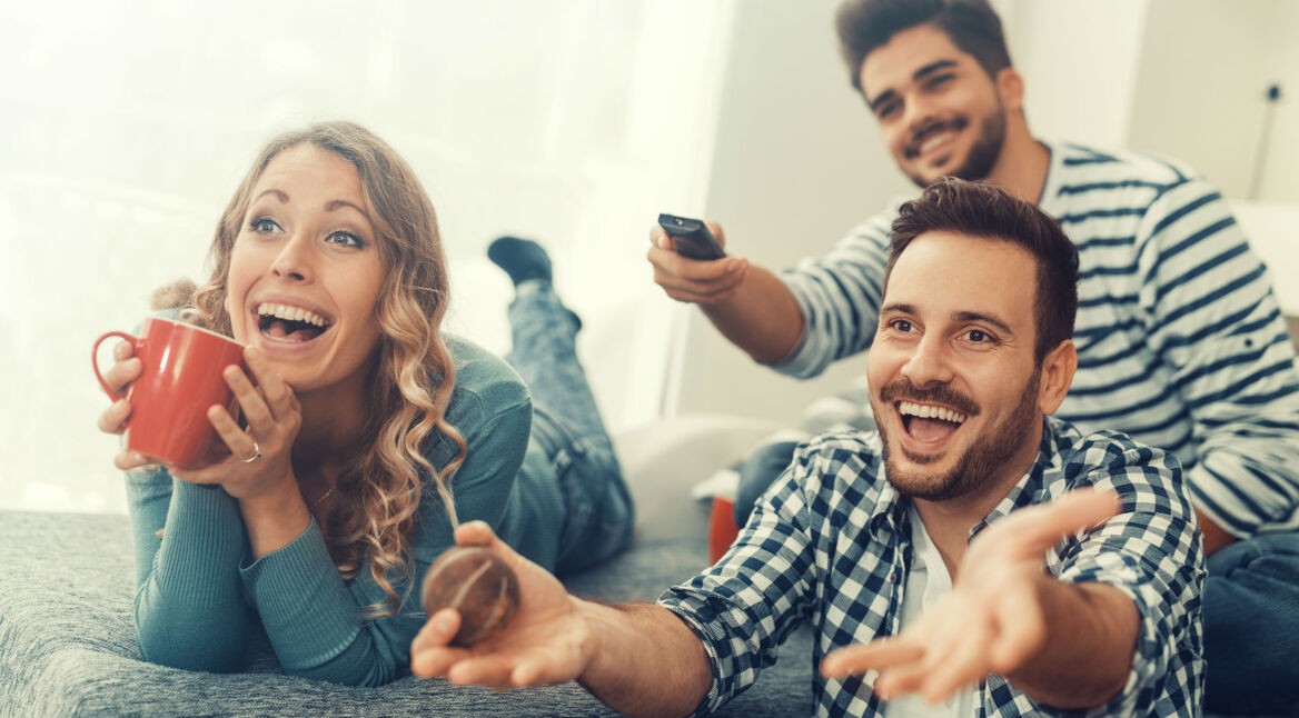 Freunde sitzen auf dem Sofa und schauen einen Film.