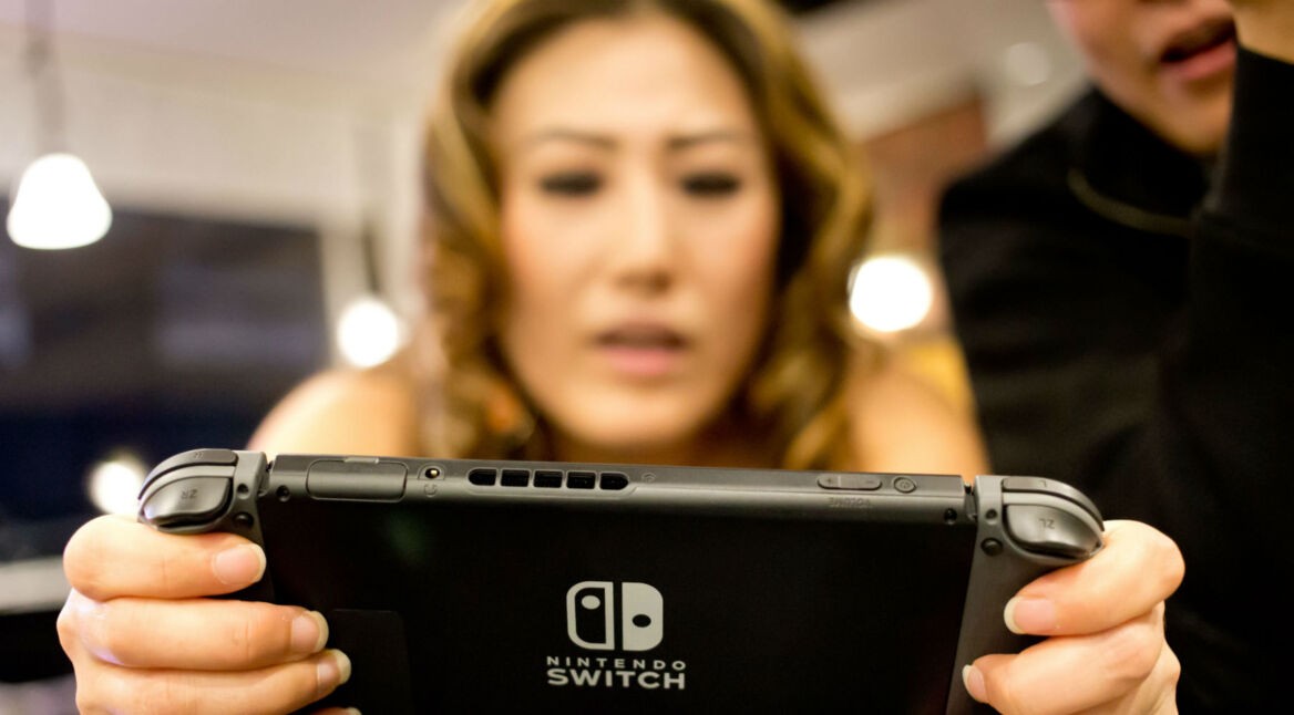Junge Frau hält Nintendo Switch in ihren Händen.