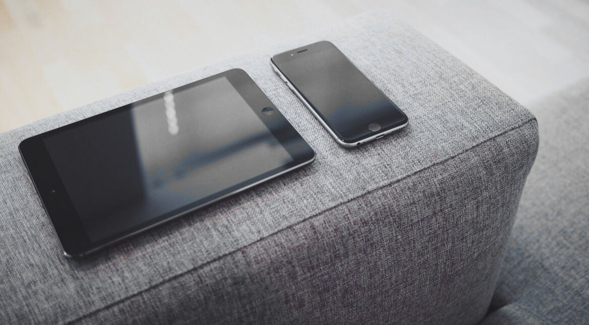 Ein iPad und ein iPhone auf dem Sofa
