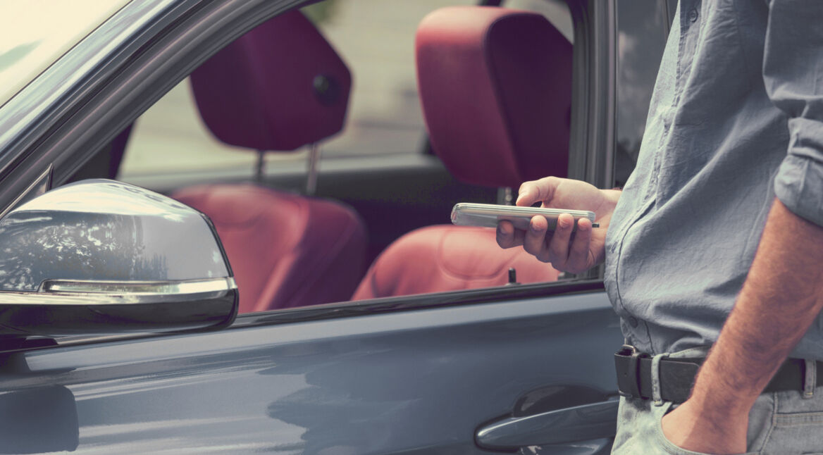 Ein Mann öffnet sein Fahrzeug mit dem Smartphone