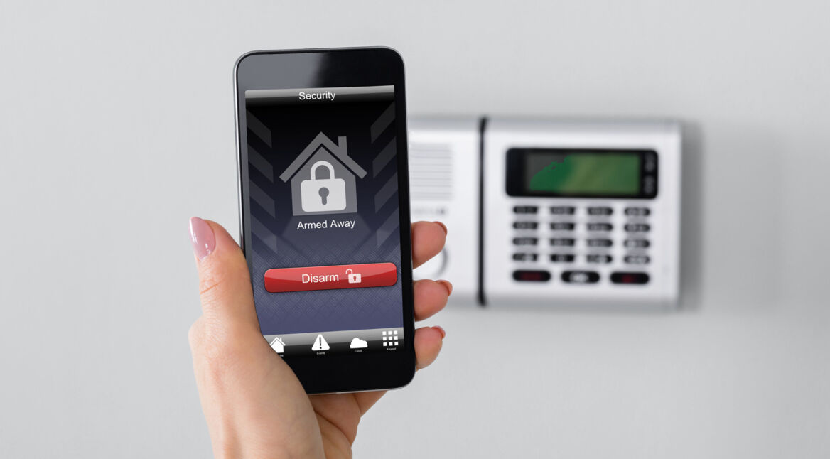 Eine Frau programmiert ihre Alarmanlage via Smartphone