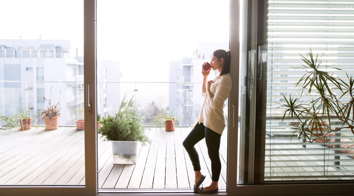 Eine Frau trinkt Kaffee am Balkon