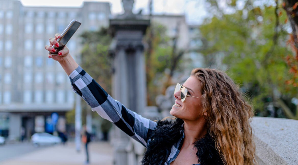Eine Frau macht Selfies vor städtischem Hintergrund