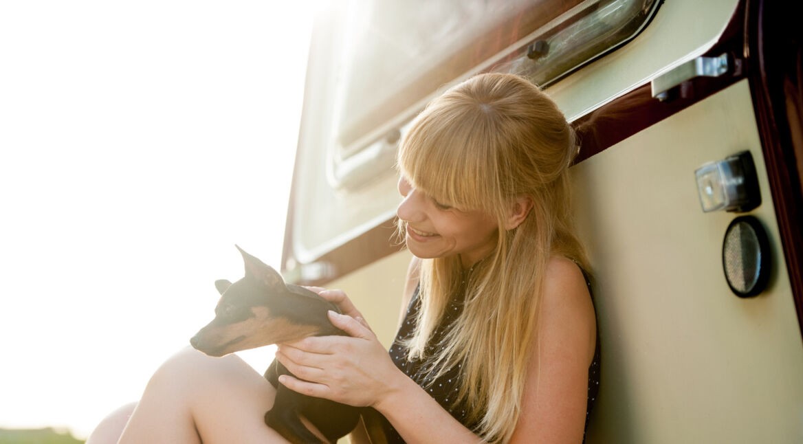 Eine junge Frau mit ihrem Wohnwagen und einem Hund