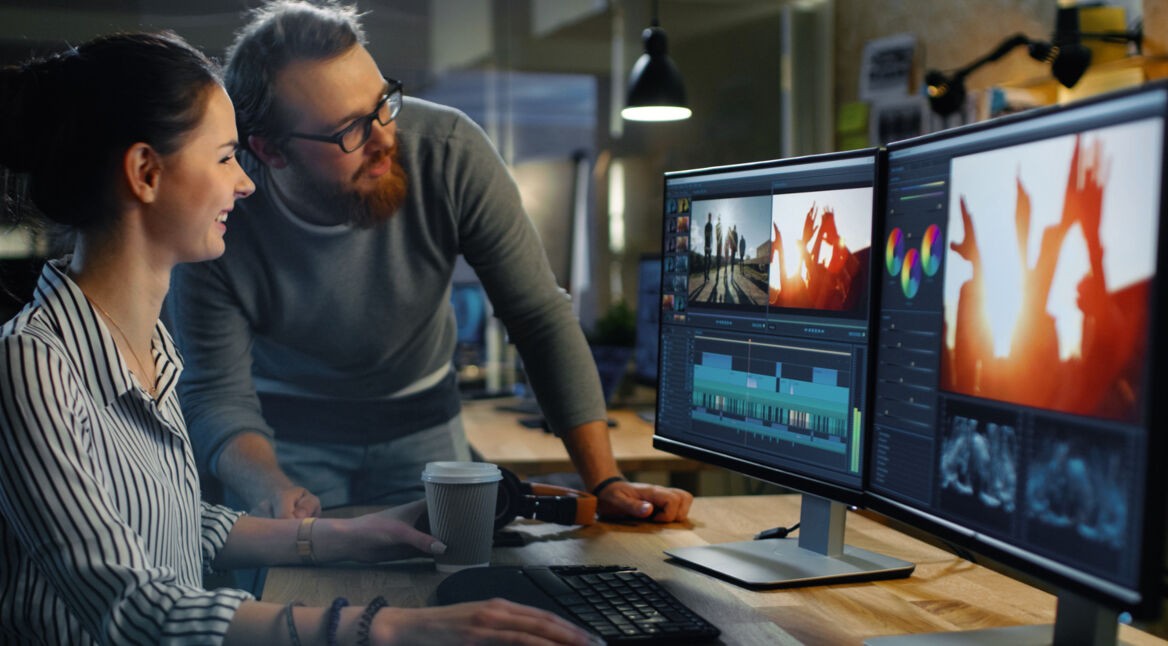 Junge Frau sitzt an einem Arbeitsplatz mit zwei Bildschirmen