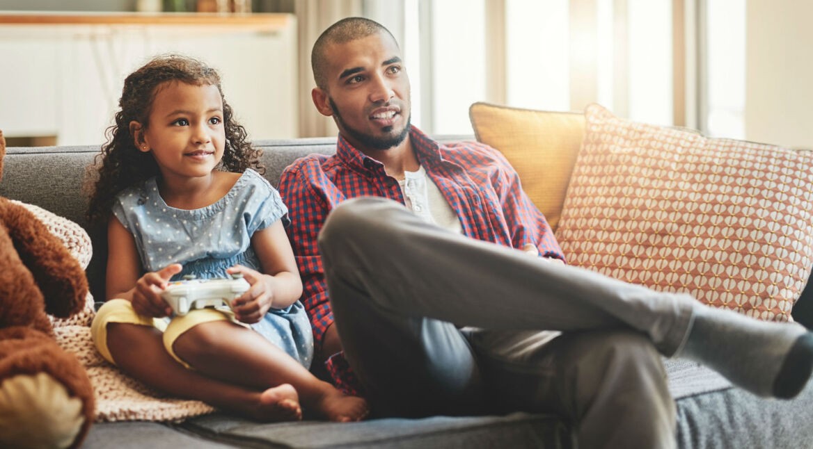 Vater und Tochter zocken Games via Controller.