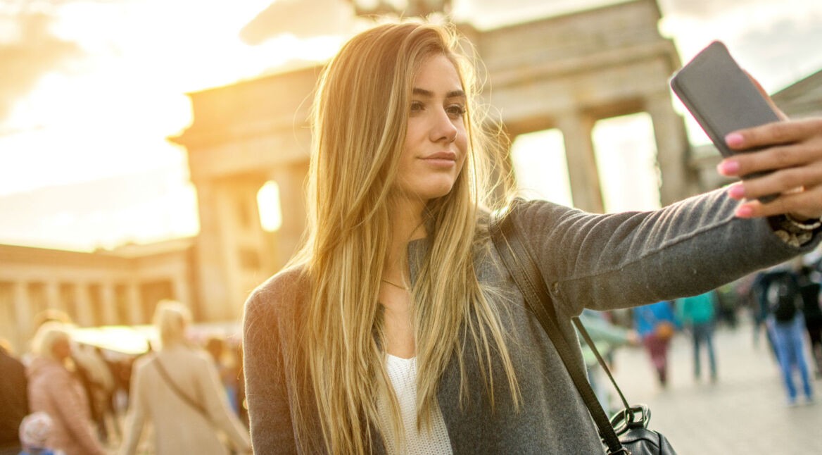 Junge Frau nimmt ein Selfie von sich mit dem Smartphone auf.