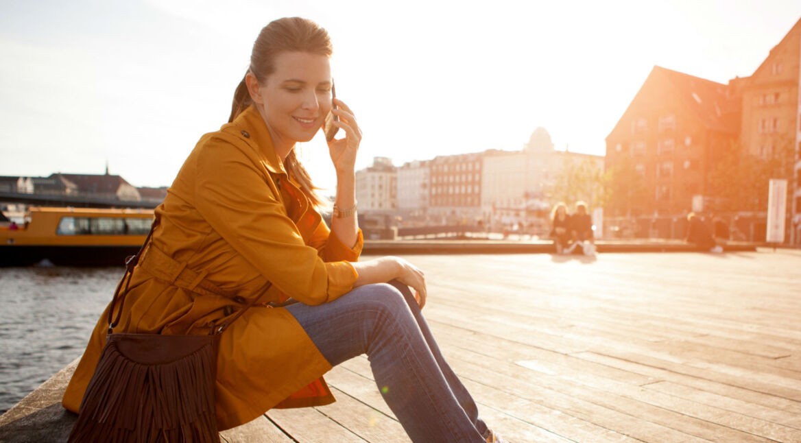 Frau telefoniert draußen mit ihrem Smartphone.