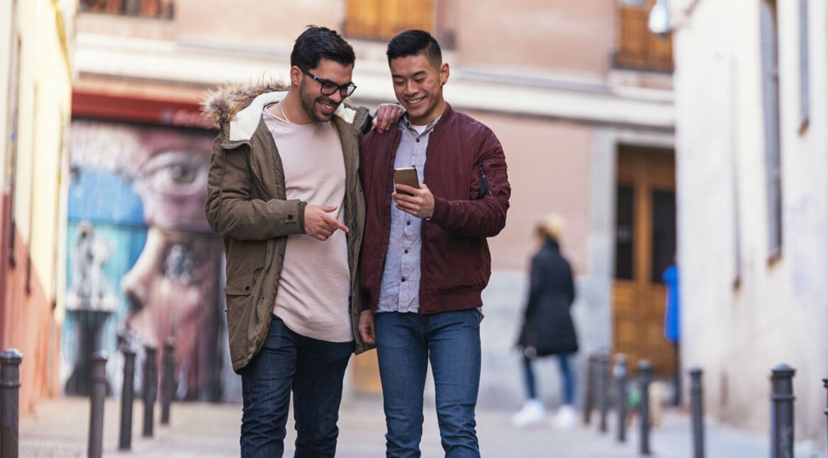 Zwei Freunde lesen WhatsApp-Nachricht auf dem Smartphone und löschen sie.