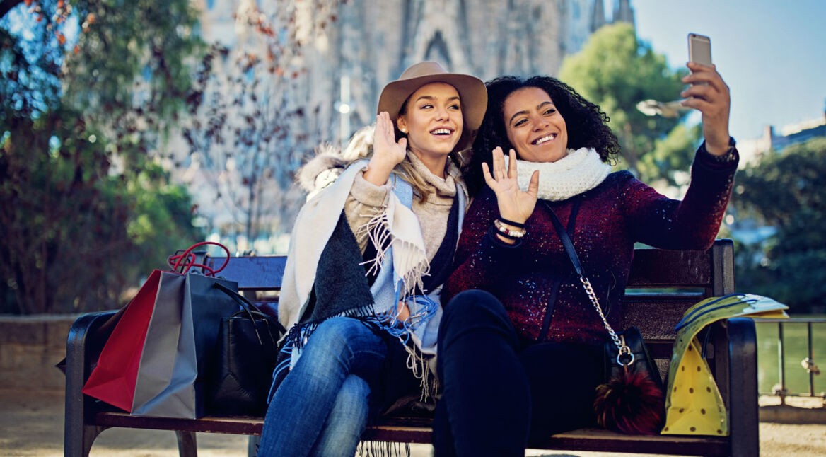 Freundinnen tätigen Videoanruf über ihr Smartphone nach dem Einkauf.