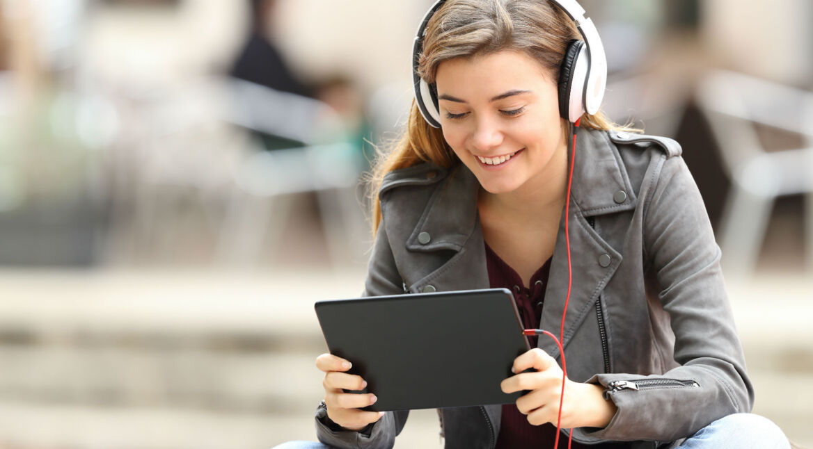 Junge Frau streamt ihre Lieblingsserie über ein Tablet.