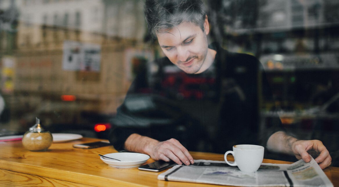 Ein Mann liest die Nachrichten in einem Cafe