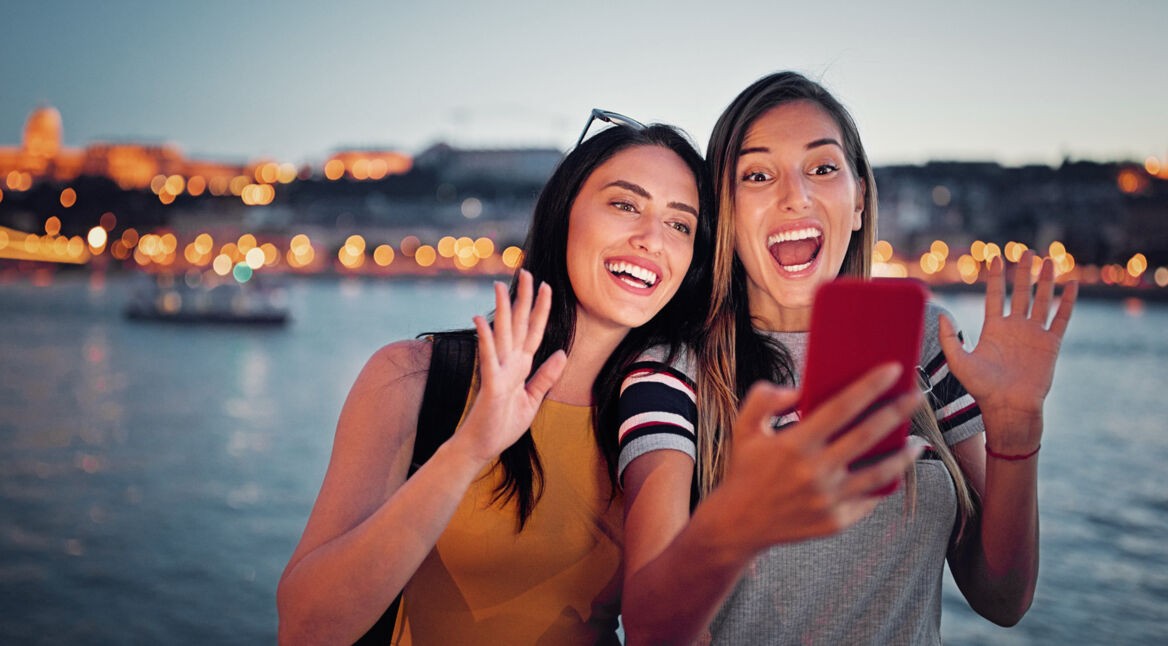Zwei junge Frauen filmen sich selbst am Wasser
