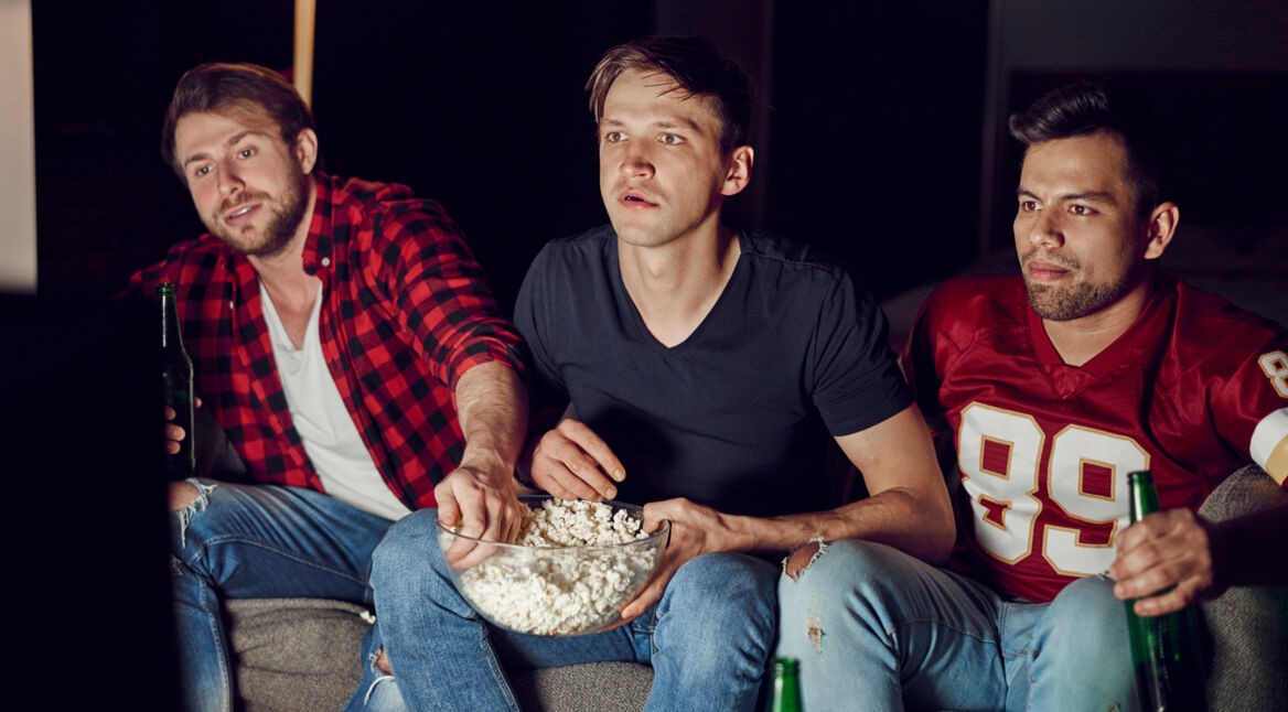 Focused men watching footaball match in the evening