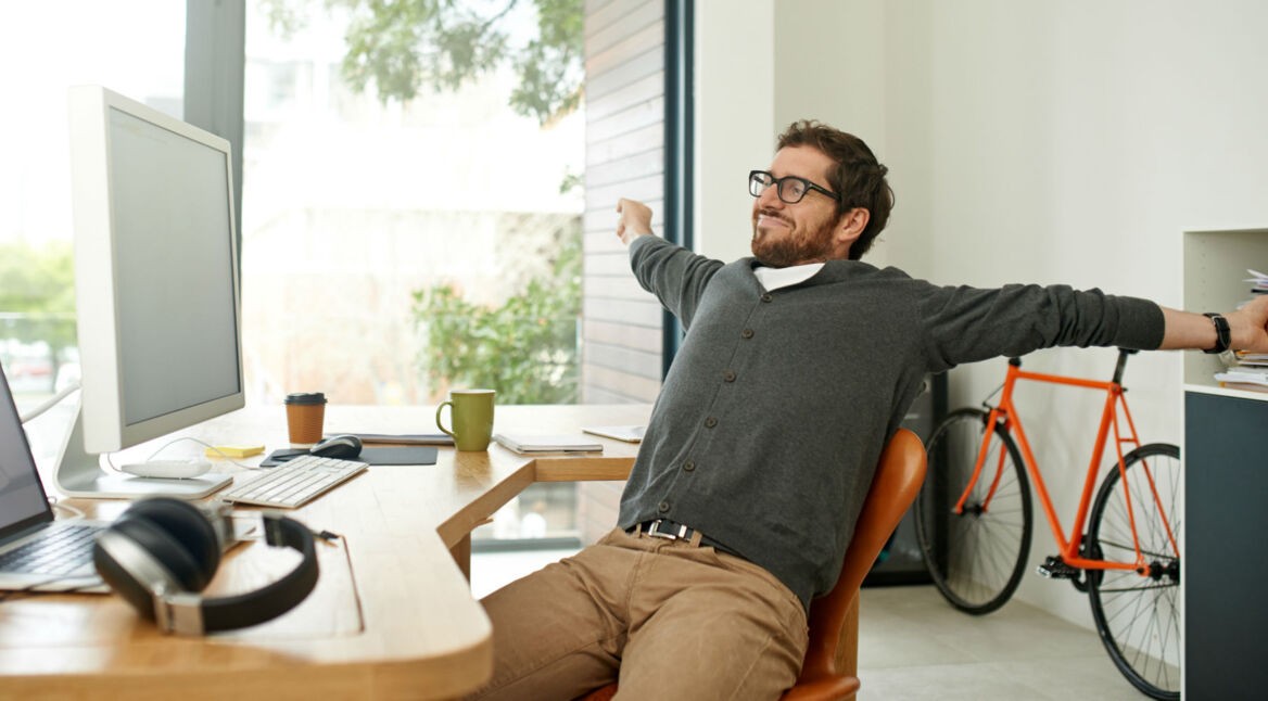 Junger Mann sitzt entspannt vor dem Computer.