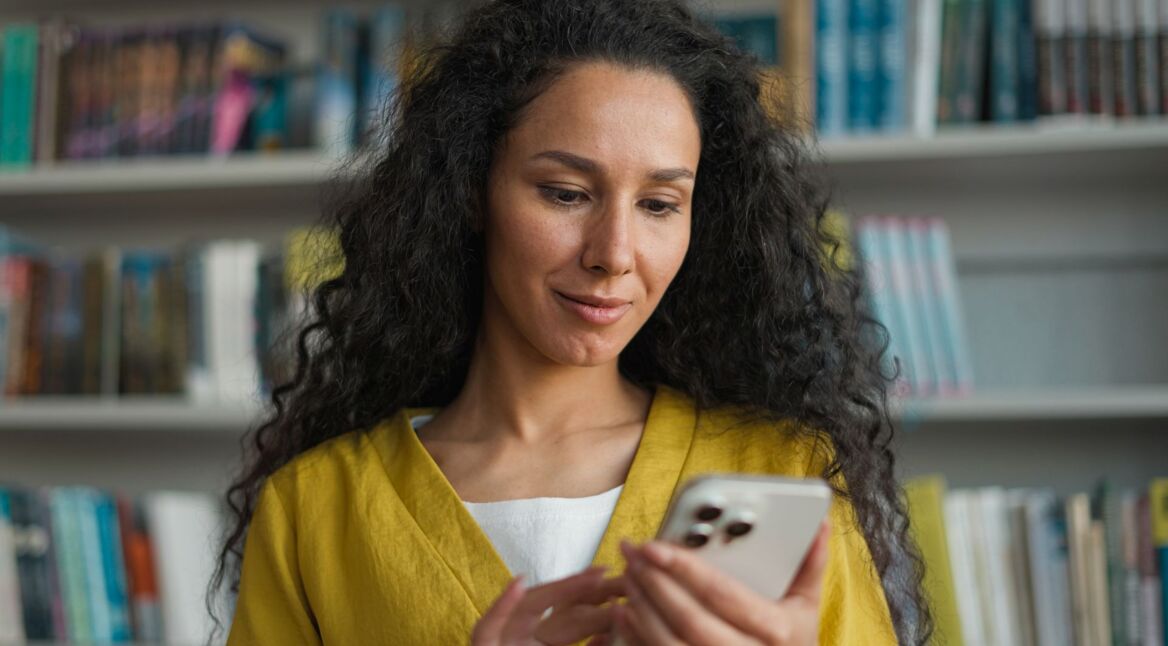 Junge Frau schaut sich etwas auf ihrem iPhone Pro an.