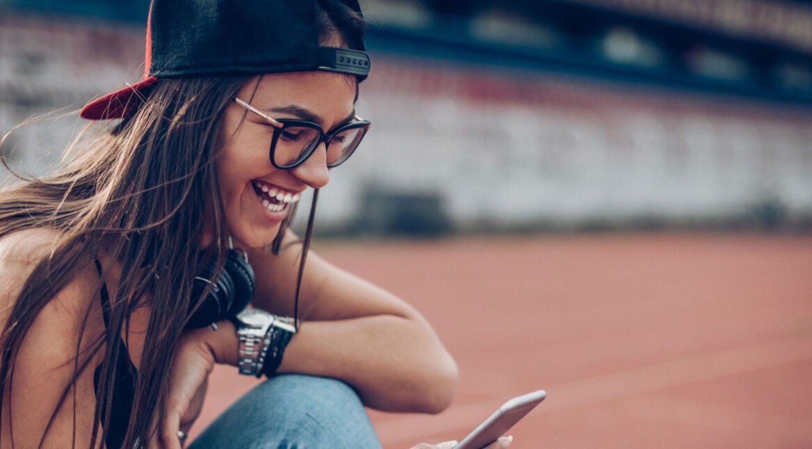 Junge Frau textet ihren Freunden über ihr Smartphone.