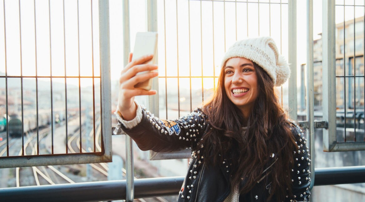Junge Frau schießt ein Selfie mit ihrem Smartphone.