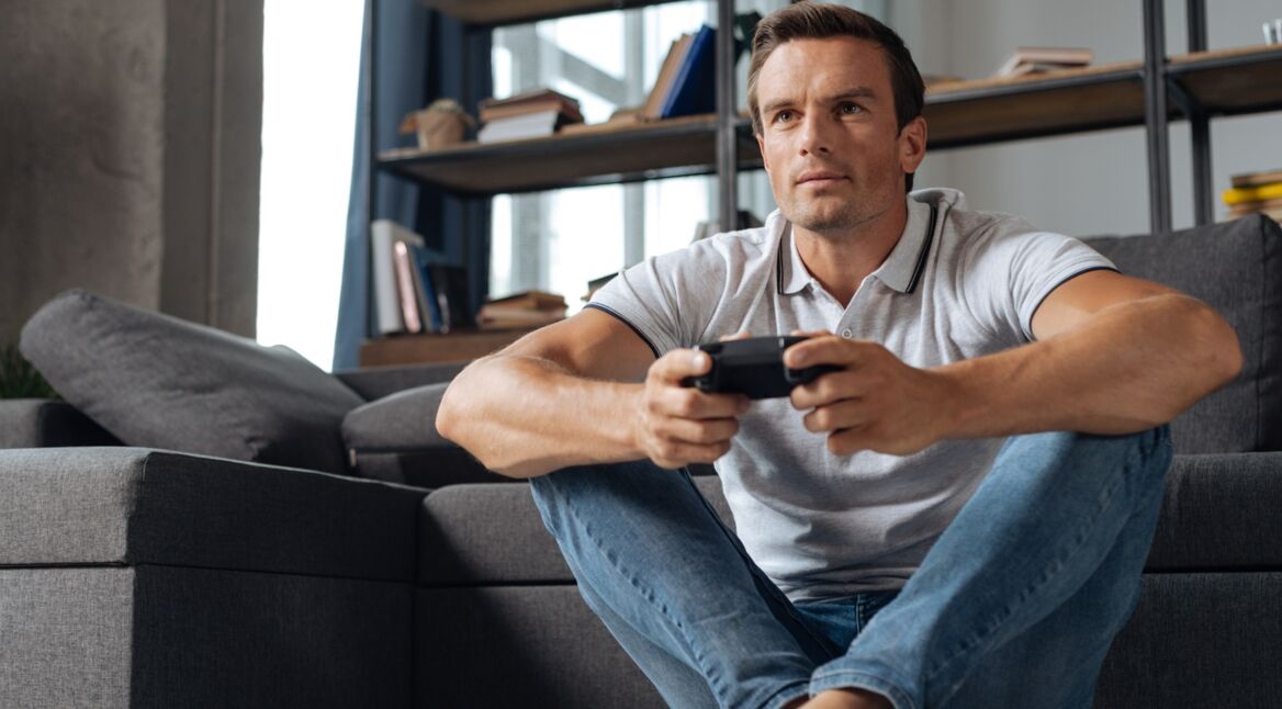 Junger Mann spielt God of War auf Konsole