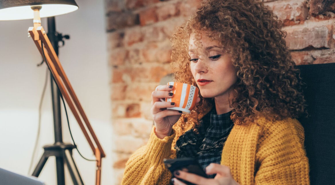 Junge Frau steuert ihr Smart Home via Smartphone.